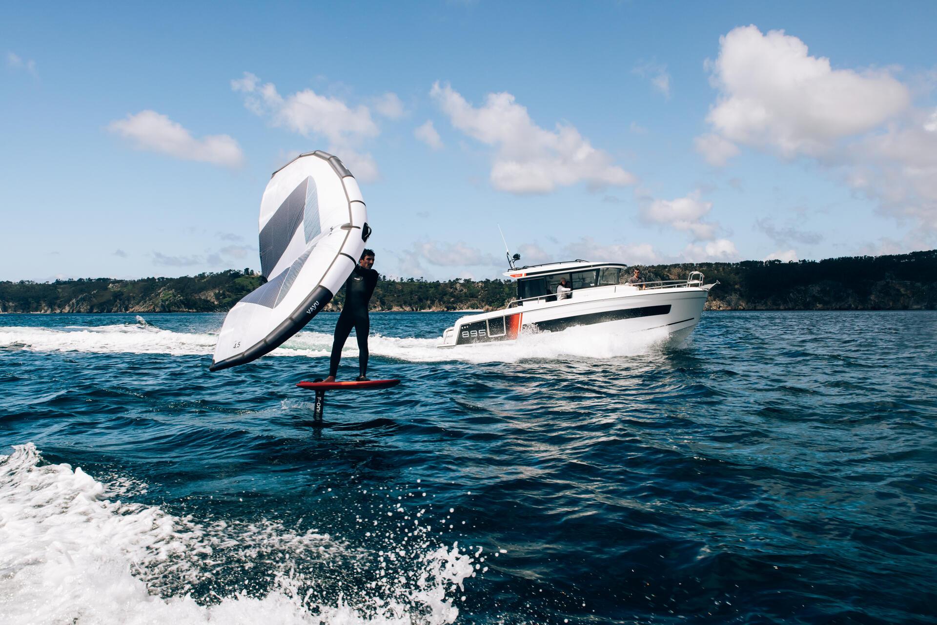 Jeanneau-Merry-fisher-895-S2-marseille-yacht-mediterranee00010 a person on a surfboard with a sail on the water with a boat Merry fisher 895 S2 in the background
